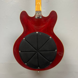 The back of a cherry 1967-68 Vox Sidewinder IV Bass (V272) by Vox features a large, black, padded circular attachment covering the semi-hollow body.