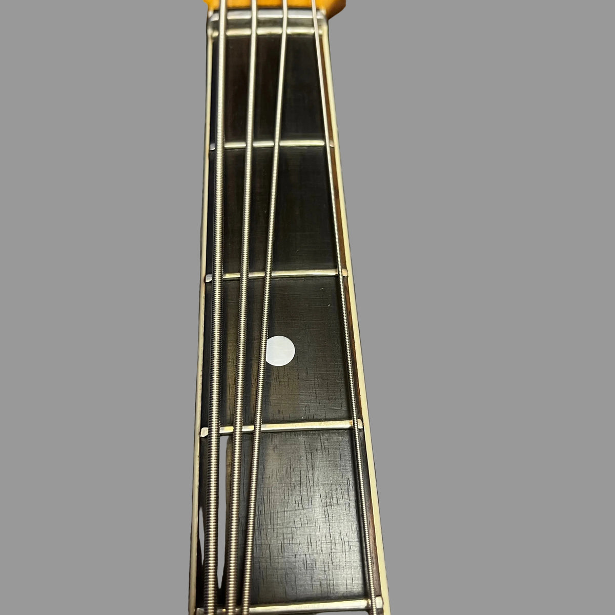Close-up of a 1967-68 Vox Sidewinder IV Bass (V272) Cherry neck by Vox, showing four metal strings, fretboard, white fret marker, and frets against a plain gray background.
