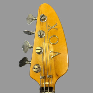 Close-up of the 1967-68 Vox Sidewinder IV Bass (V272) Cherry headstock, featuring four tuning pegs and the VOX brand in metal letters, highlighting this vintage Italian classic on a gray background.