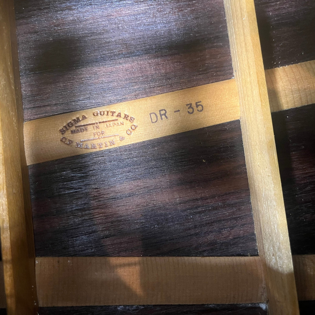 Close-up of a Vintage Sigma DR-35 Acoustic Guitar interior shows the "SIGMA GUITARS MADE IN JAPAN FOR C.F. MARTIN & CO. DR-35" stamp, wood braces, and grain, highlighting this Sigma model inspired by the Martin D-35. Includes case.