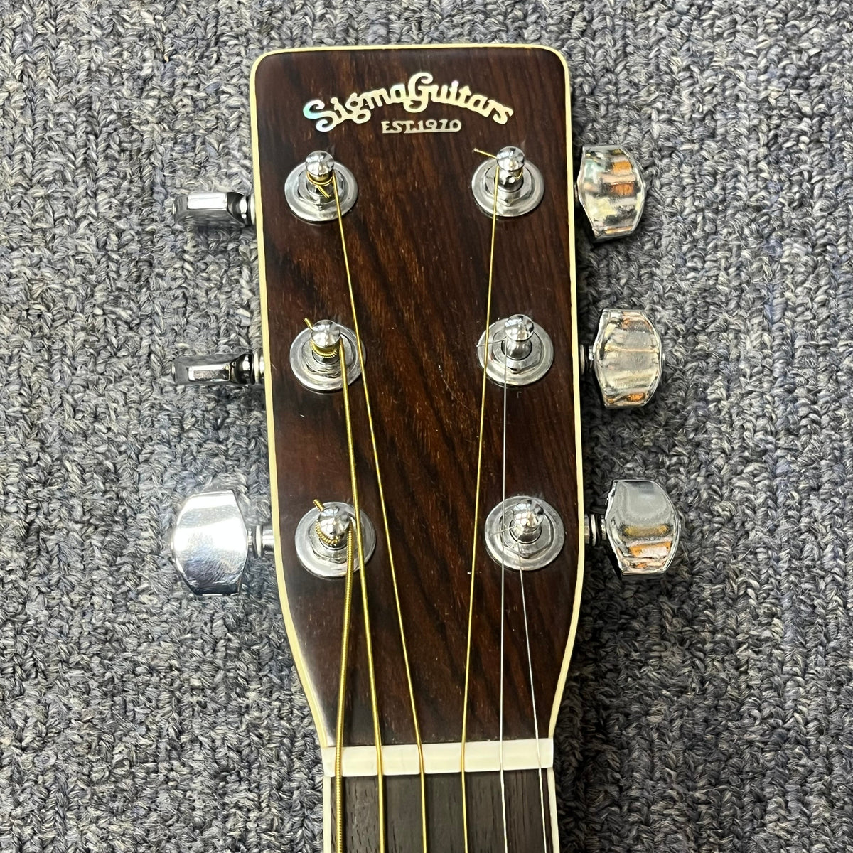 Close-up of a Vintage Sigma DR-35 Acoustic Guitar headstock (Made in Japan) by Sigma, showing six tuning pegs on a textured gray carpet background.