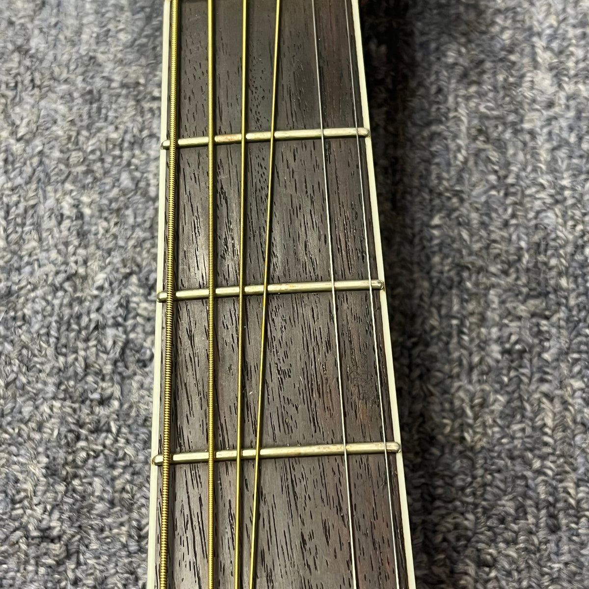 Close-up of the fretboard with four metal strings and visible frets, set against textured gray fabric—this is a vintage Sigma DR-35 acoustic guitar (Made in Japan), inspired by the Martin D-35, sold with case.