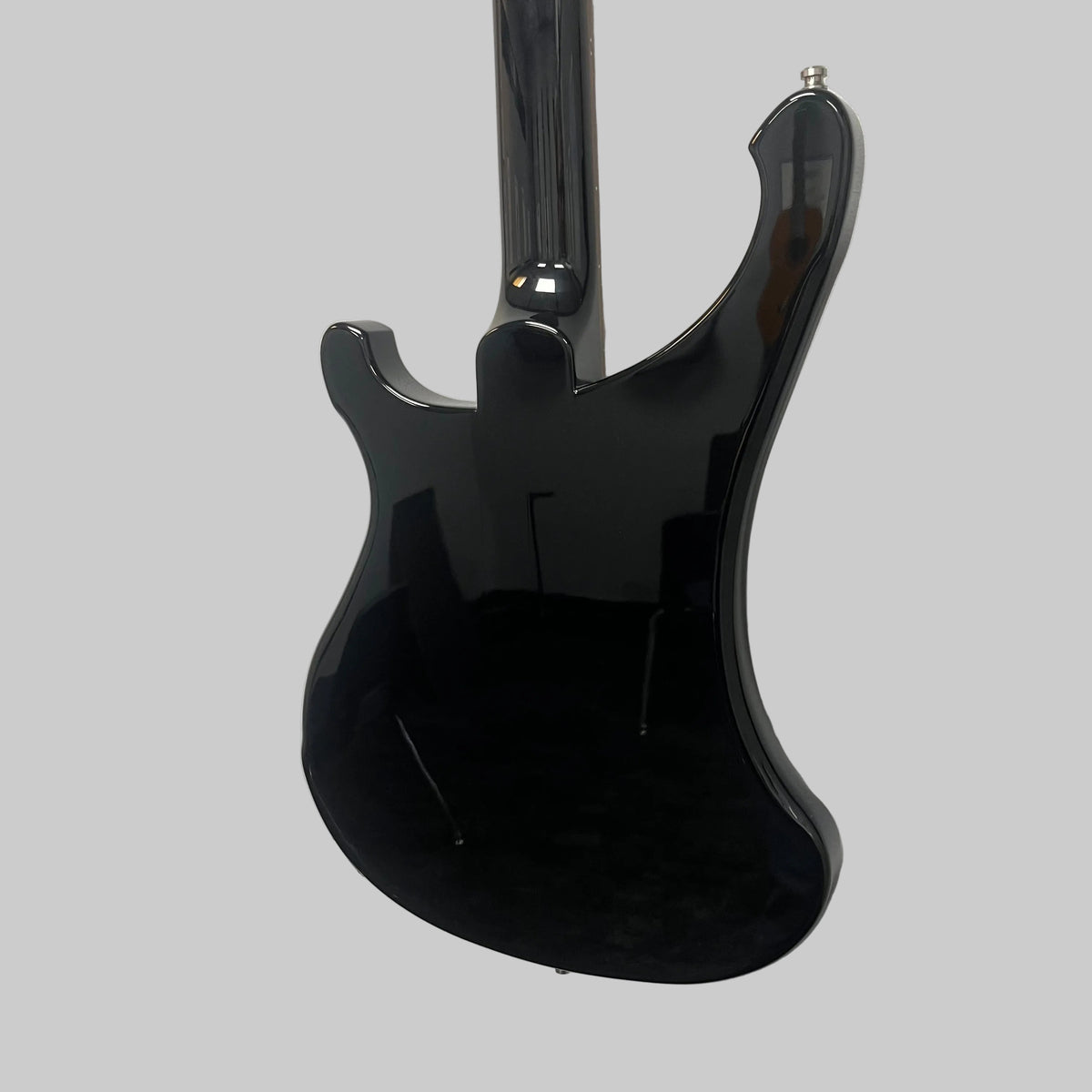 A Rickenbacker 4003 Bass Guitar – 2020 Jetglo w/Case by Rickenbacker is hanging on a white wall, photographed from the back to showcase its glossy black finish and the reflections of the room.