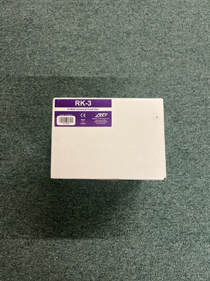A white rectangular RTI RK-3 In-Wall Universal Controller by Remote Technologies Inc sits on green carpet, perfect as a home automation in-wall controller.