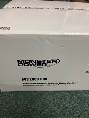 A white Monster Power AVS 2000 PRO Professional Reference Automatic Voltage Stabilizer rests on a green surface, making it an excellent choice as a professional studio power conditioner.