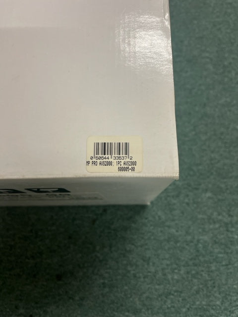 A close-up of a white box with a barcode sticker labeled “HP PRO AWS2000, PRC AWS2000, 600065-00,” possibly for the Monster Power AVS 2000 PRO Professional Reference Automatic Voltage Stabilizer by Monster Power, on a green surface.