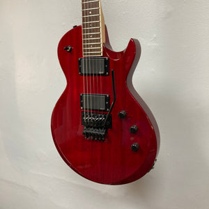 An ESP Standard Eclipse Transparent Cherry Red electric guitar with black hardware, two humbuckers, and a tremolo bridge hangs on a plain white wall.
