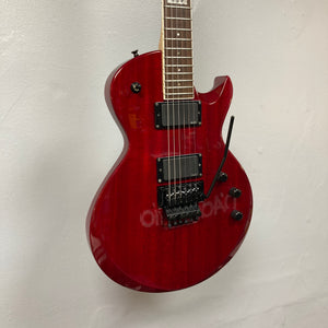 An ESP Standard Eclipse Transparent Cherry Red electric guitar by Esp, with case, dual humbuckers, and tremolo bridge, hangs against a plain white wall.