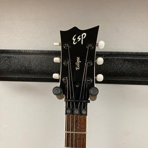 Headstock of an ESP Standard Eclipse Transparent Cherry Red guitar with tuning pegs and part of the fretboard visible, mounted on a wall hanger against a light background. Includes case. Brand: Esp.