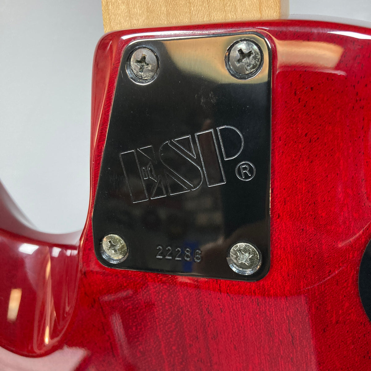 Close-up of the neck plate on an ESP Standard Eclipse Transparent Cherry Red w/Case guitar, displaying the Esp logo, four screws, and serial number 22286 engraved on this high-performance instrument.