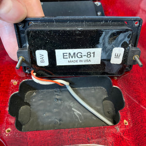 Close-up of a hand lifting an EMG-81 pickup labeled "Made in USA," showing internal wiring and the pickup cavity of an ESP Standard Eclipse Transparent Cherry Red w/Case guitar by ESP.