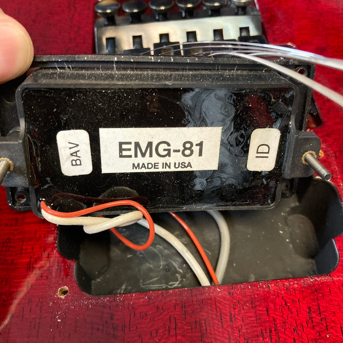 A close-up of an ESP Standard Eclipse Transparent Cherry Red guitar with its EMG-81 pickup partially removed, revealing the wiring and a "EMG-81 MADE IN USA" label. Includes case.