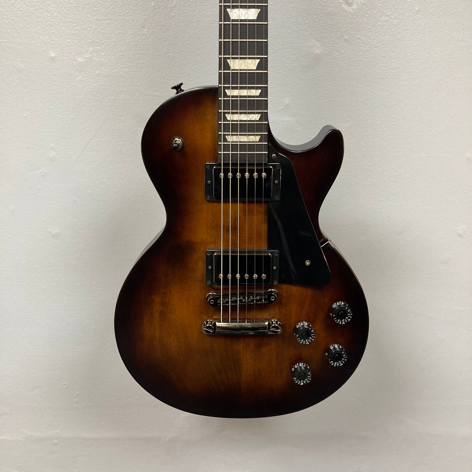 A 2025 Gibson Les Paul Studio Modern in Smokehouse Satin, featuring black pickups, four control knobs, a black pickguard, and photographed against a white background. Includes Gator Molded Case. A 2025 Gibson Les Paul Studio Modern in Smokehouse Satin, featuring black pickups, four control knobs, a black pickguard, and photographed against a white background. Includes Gator Molded Case.