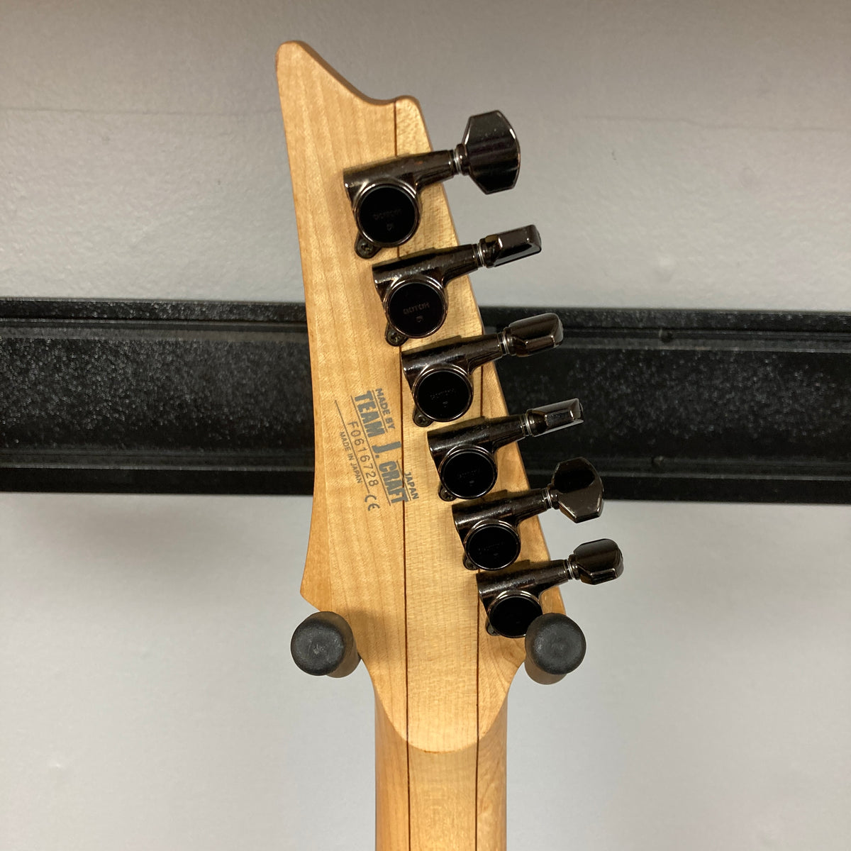 Close-up of the Ibanez Prestige RG1570 Cosmic Blue's headstock, showing six black tuning pegs, manufacturer labels, and the signature Wizard Prestige neck. Includes case. Brand: Ibanez.