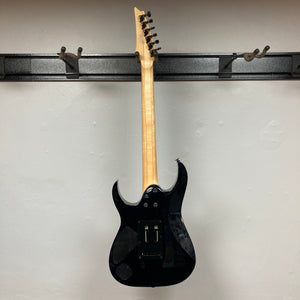 A Cosmic Blue Ibanez Prestige RG1570 electric guitar by Ibanez, shown hanging on a wall mount from the back, displays its tuning pegs, electronics cavity cover, and signature Wizard Prestige neck. Includes case.