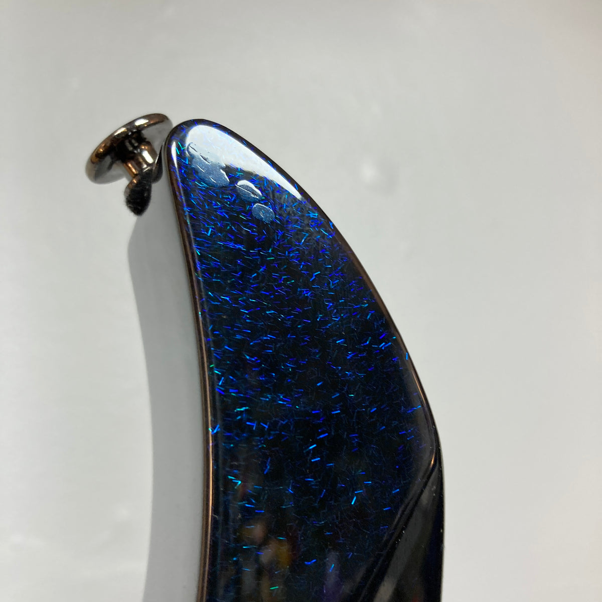 Close-up of the Ibanez Prestige RG1570 Cosmic Blue headstock, showcasing its shimmering dark blue finish with iridescent specks, a tuning peg, and a simple light background. Includes case.