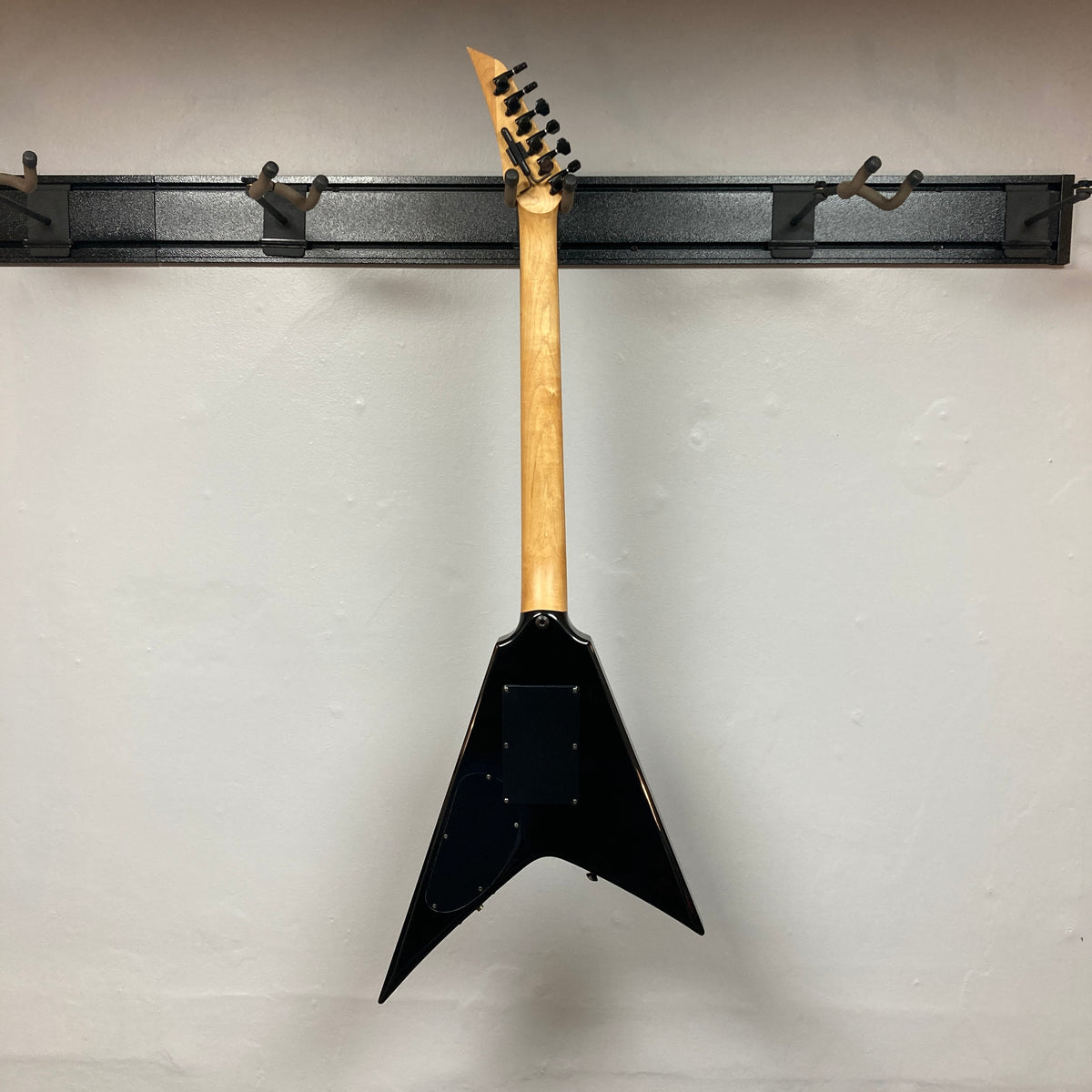 A 1992 Carvin Ultra V USA with Kahler Steeler Trem and MJ-wound Seymour Duncan DCJ pickups hangs by its headstock on a wall-mounted rack, showcasing the sleek back.