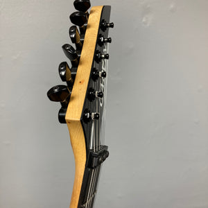Close-up of a 1992 Carvin Ultra V USA headstock with six tuners and metal strings, featuring a Kahler Steeler Trem and MJ-wound Seymour Duncan DCJ, set against a plain light-colored wall.