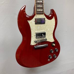 Gibson SG Standard Heritage Cherry yr 2000 Consign electric guitar with double-cutaway body, white pickguard, four control knobs, and chrome hardware by Gibson, made in USA and displayed against a light-colored wall.