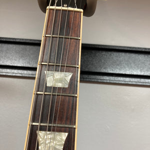 Close-up of a Gibson SG Standard Heritage Cherry yr 2000 Consign guitar neck, featuring six strings, two rectangular mother-of-pearl inlays, and frets set against a light background.