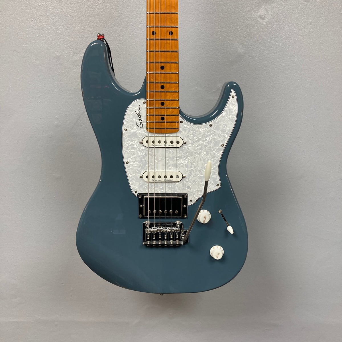 The Godin Session T-Pro Arctik Blue MN SF with Bag features a maple neck, white pickguard, HSS pickups, and tremolo bridge by Godin, displayed against a plain gray background.