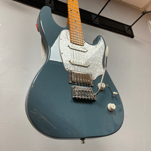 The Godin Session T-Pro Arctik Blue MN SF with Bag, a blue electric guitar by Godin featuring a maple neck, white pickguard, HSS pickups, and whammy bar, is shown hanging on a wall.