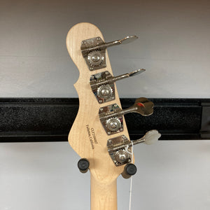 The headstock of a G&L L-2000 USA Tobacco Sunburst Bass w/Case Used, featuring four tuning pegs, is displayed on a wall hanger against a plain background, highlighting the classic G&L design.