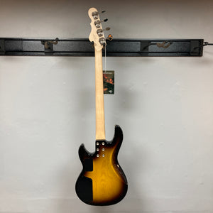 A G&L L-2000 USA Tobacco Sunburst Bass w/Case Used by G&L hangs on the wall, displayed from the back with its light wood neck and an attached tag visible.