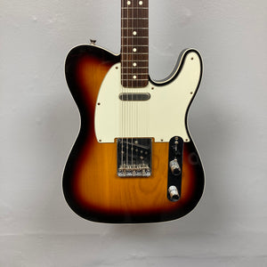 A Fender Heritage '60s Telecaster Custom Made in Japan Sunburst electric guitar with a white pickguard and two control knobs is displayed against a plain light gray background. Comes with gigbag; consign item.