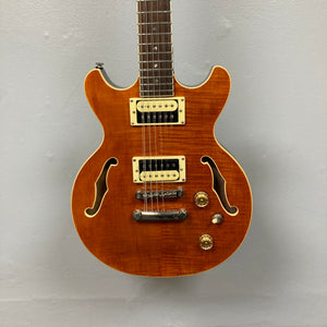The Dean Boca Trans Amber Burst 12 String w/Gigbag by Dean is shown with a striking amber burst finish, twelve strings, two pickups, four control knobs, and two f-holes against a plain light gray background.