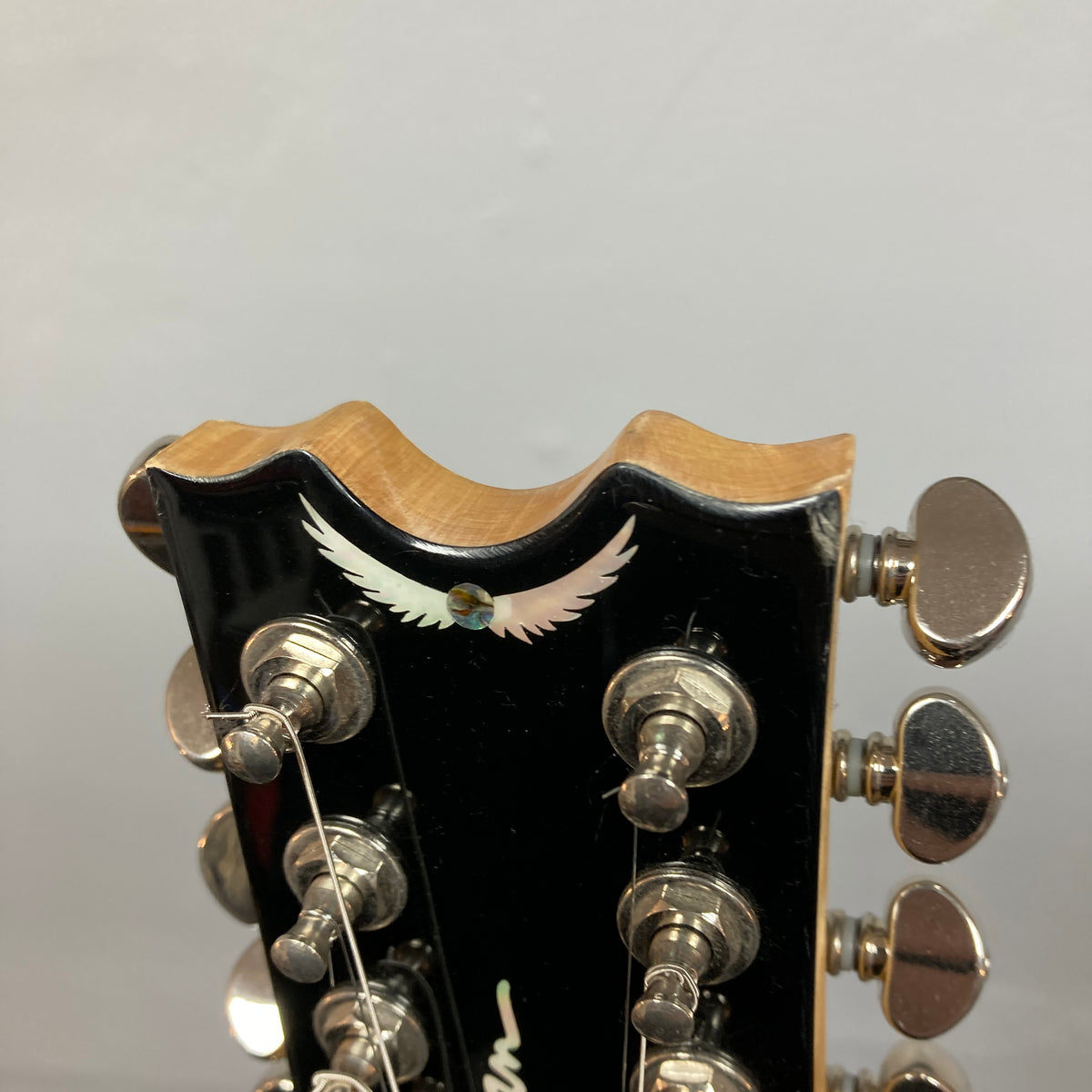 Close-up of a Dean Boca Trans Amber Burst 12 String headstock with twelve tuning pegs and an inlaid white bird design, ideal for fans of the semi hollow body guitar style. Includes gigbag.
