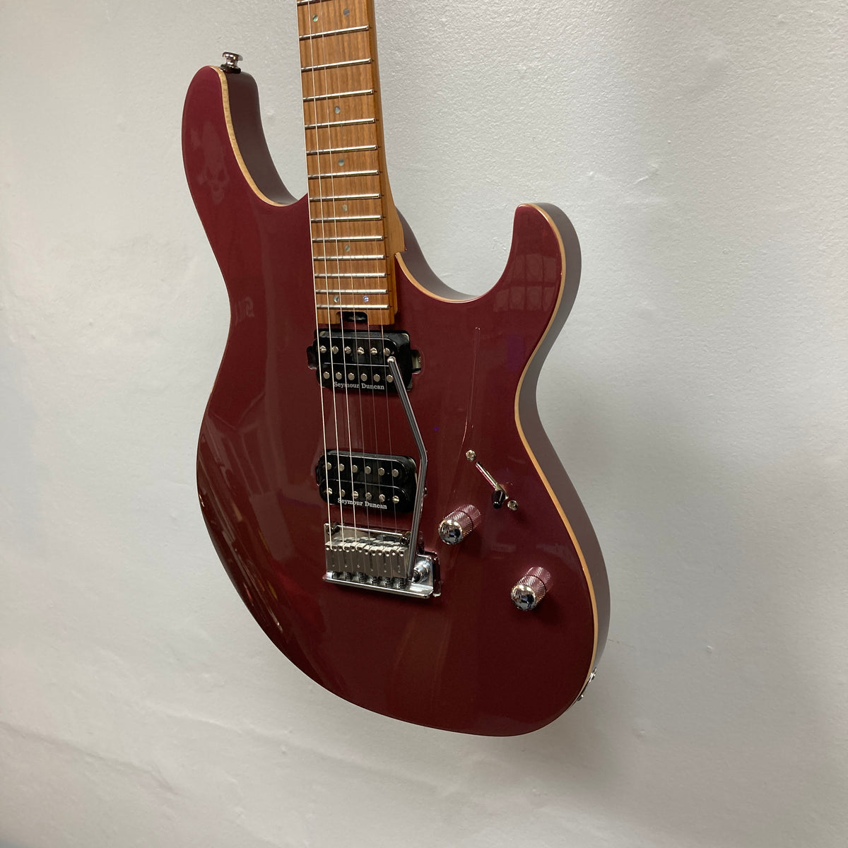 A Cort FW-G300 PRO Vivid Burgundy electric guitar with a maple neck, two humbucker pickups, and chrome hardware is mounted on a white wall.