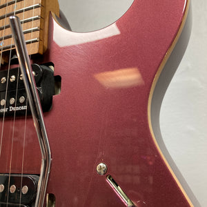 Close-up of the Cort FW-G300 PRO Vivid Burgundy electric guitar body, featuring its pickups, strings, whammy bar, and part of the neck against a plain light-colored wall.