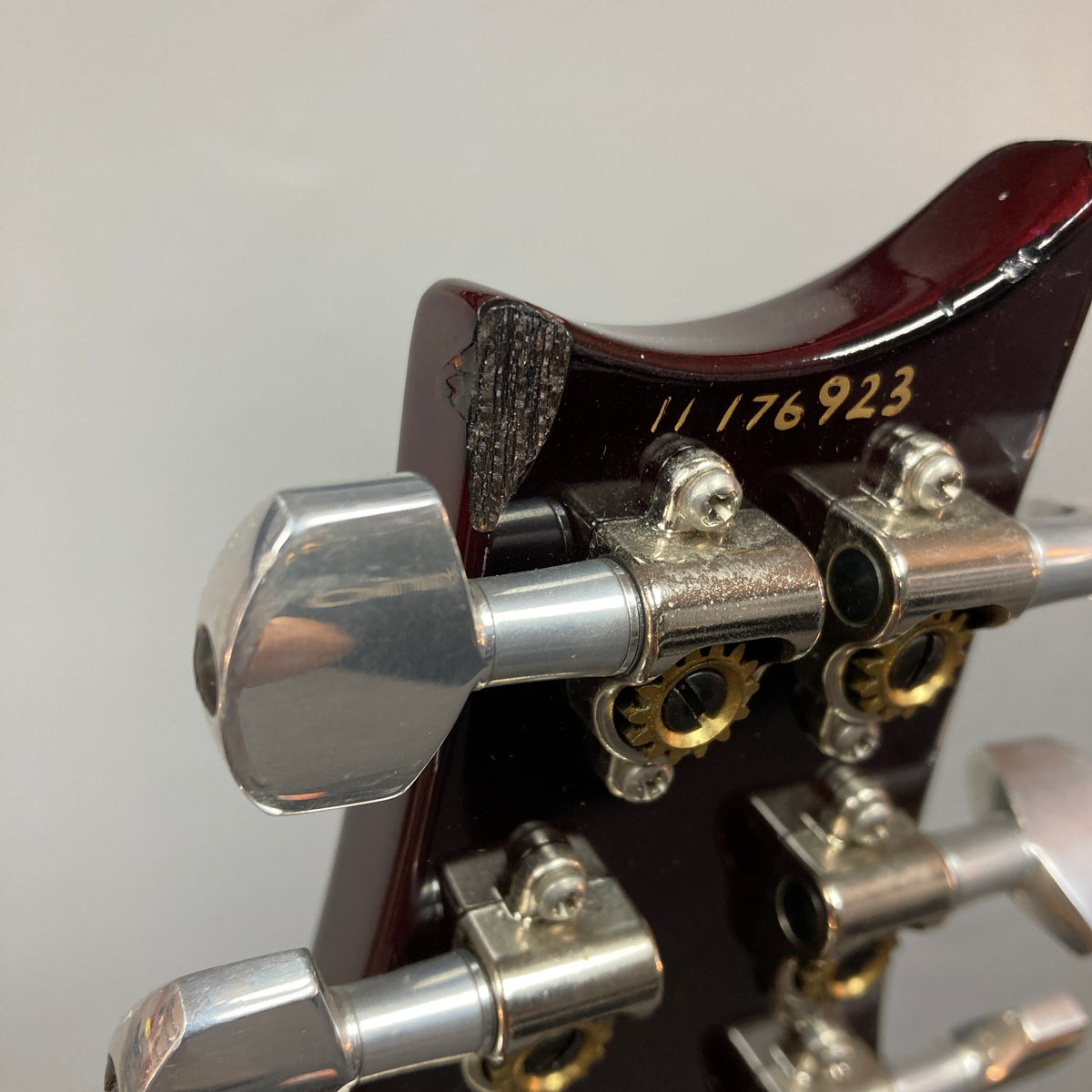 Close-up of the headstock on a PRS Custom 24 Violet 2011 electric guitar by PRS, serial number 11 176923, highlighting damaged wood near one tuning machine.
