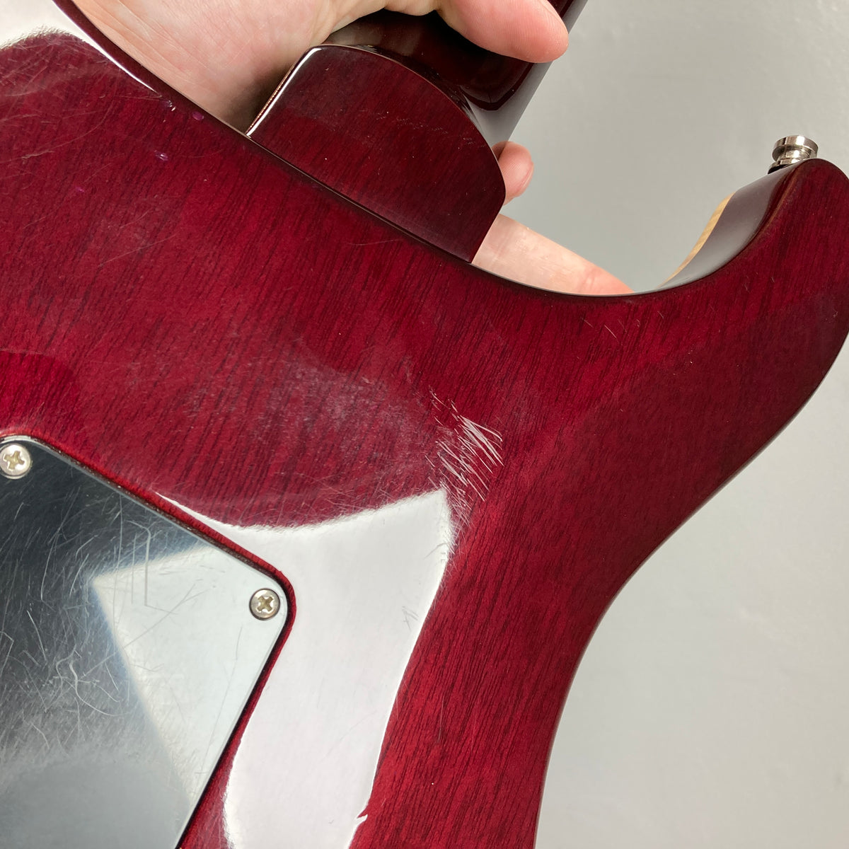 Close-up of the back of a PRS Custom 24 Violet 2011 electric guitar by PRS, showing visible scratches and wear near the neck joint and plastic backplate.