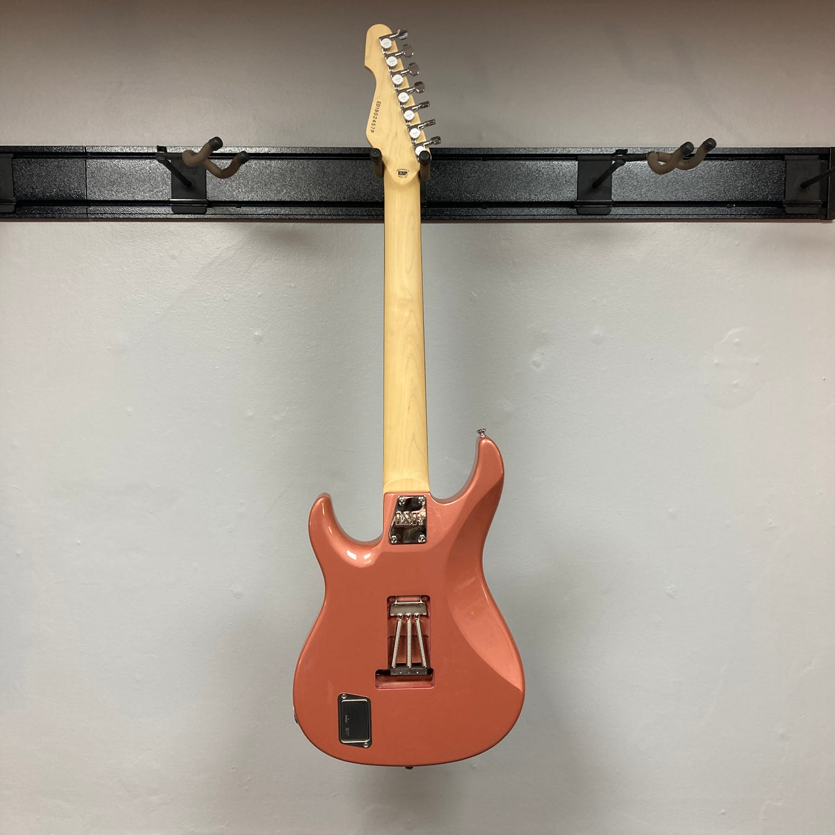 An Edwards E-SN7-194MF Mikio Fujioka Signature seven-string guitar in Burgundy Mist, made by Edwards, hangs on a black wall mount and is pictured from the back against a plain light-colored wall.