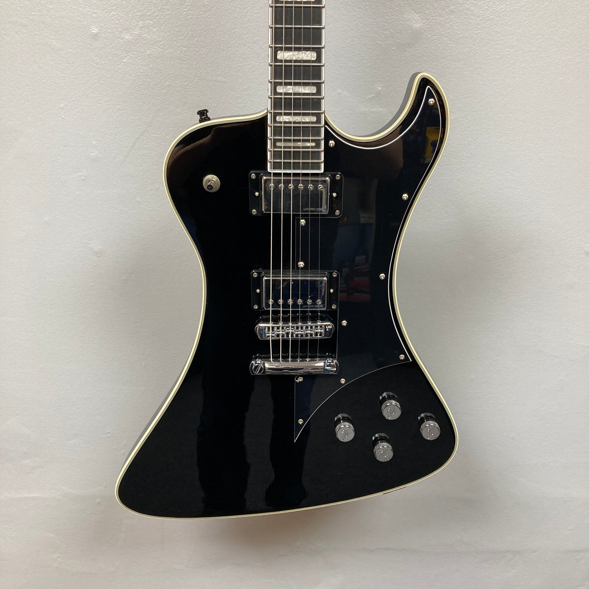 The Hagstrom Fantomen Custom Black w/case electric guitar by Hagstrom, featuring a distinctive offset body shape, chrome hardware, two Lundgren Design humbucker pickups, four control knobs, and white binding, is photographed against a plain white background.