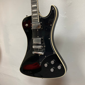 The Hagstrom Fantomen Custom Black w/case electric guitar by Hagstrom features a glossy black finish, cream binding, chrome hardware, a pair of Lundgren Design humbuckers, four control knobs, and a three-way pickup selector switch. It is displayed hanging against a white wall.