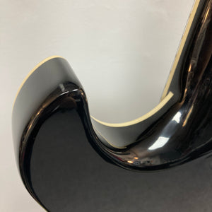 Close-up of a Hagstrom Fantomen Custom Black w/case electric guitar body, featuring its glossy black finish, curved cutaway edge, and cream binding against a plain background.