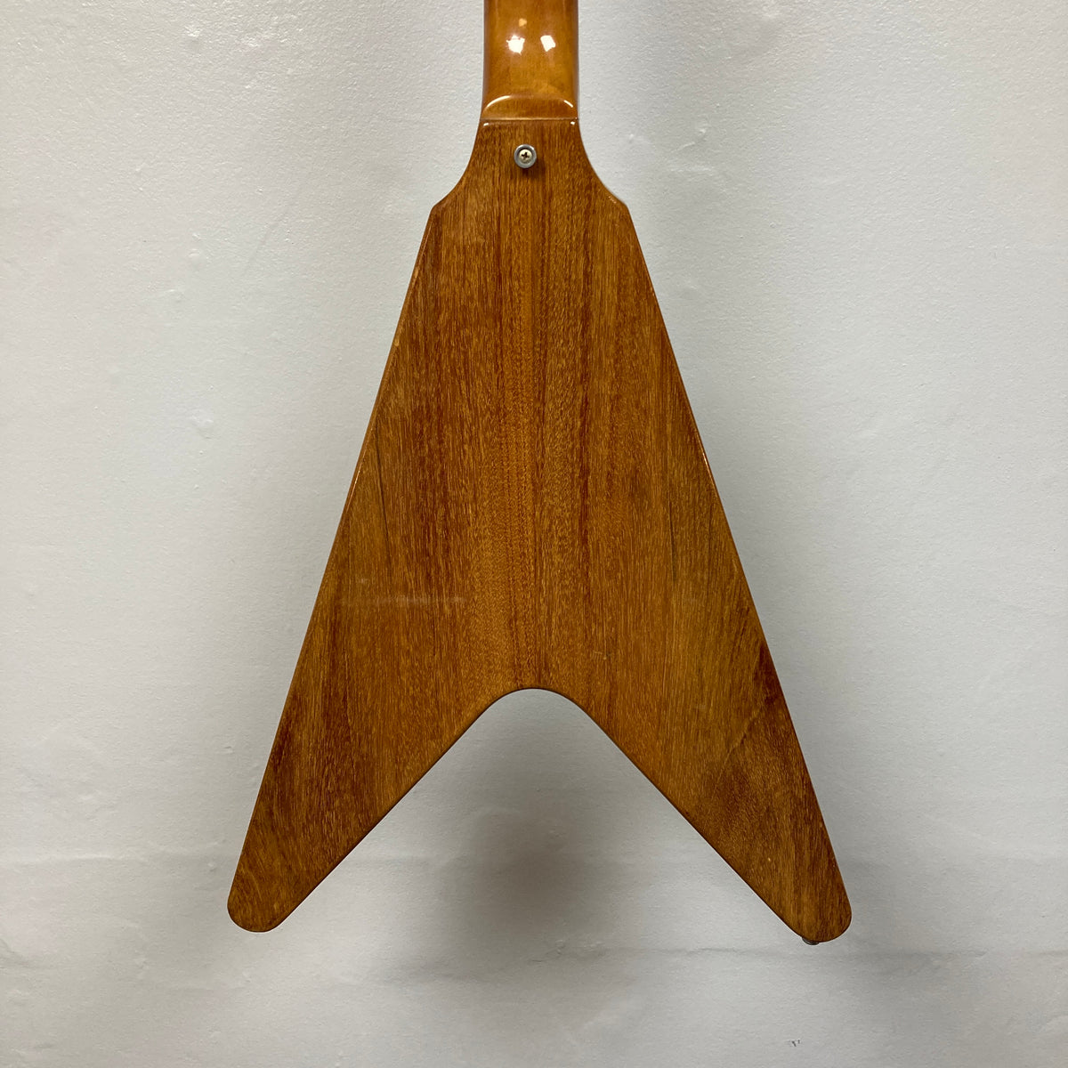 Back view of a 1975 Gibson Flying V electric guitar body with a distinctive V-shaped design, reminiscent of vintage models, showcased against a plain white background.