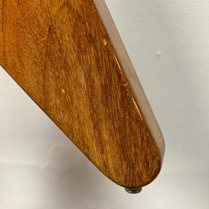 Close-up of a 1975 Gibson Flying V by Gibson with a glossy natural finish, showing some scratches and featuring a small round knob at the bottom, reminiscent of a vintage Flying V guitar, against a plain white background.