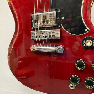 Close-up of a 1977 Gibson SG Standard Cherry electric guitar by Gibson, featuring its rich mahogany body, dual pickups, four control knobs, selector switch, and portions of the bridge and pickguard—a classic instrument from the renowned Gibson Kalamazoo era.