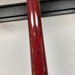 Close-up of the 1977 Gibson SG Standard Cherry by Gibson, its red glossy neck bearing visible scratches—set against a white wall and black horizontal rack, evoking the craftsmanship of the celebrated Kalamazoo era.