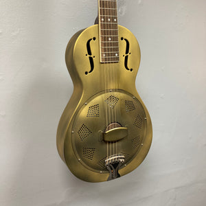 The Republic Parlor Resolian Antique Bronze Resonator w/Case by Republic, featuring a metallic body with f-shaped sound holes and a single cone, is mounted vertically against a plain light gray wall.