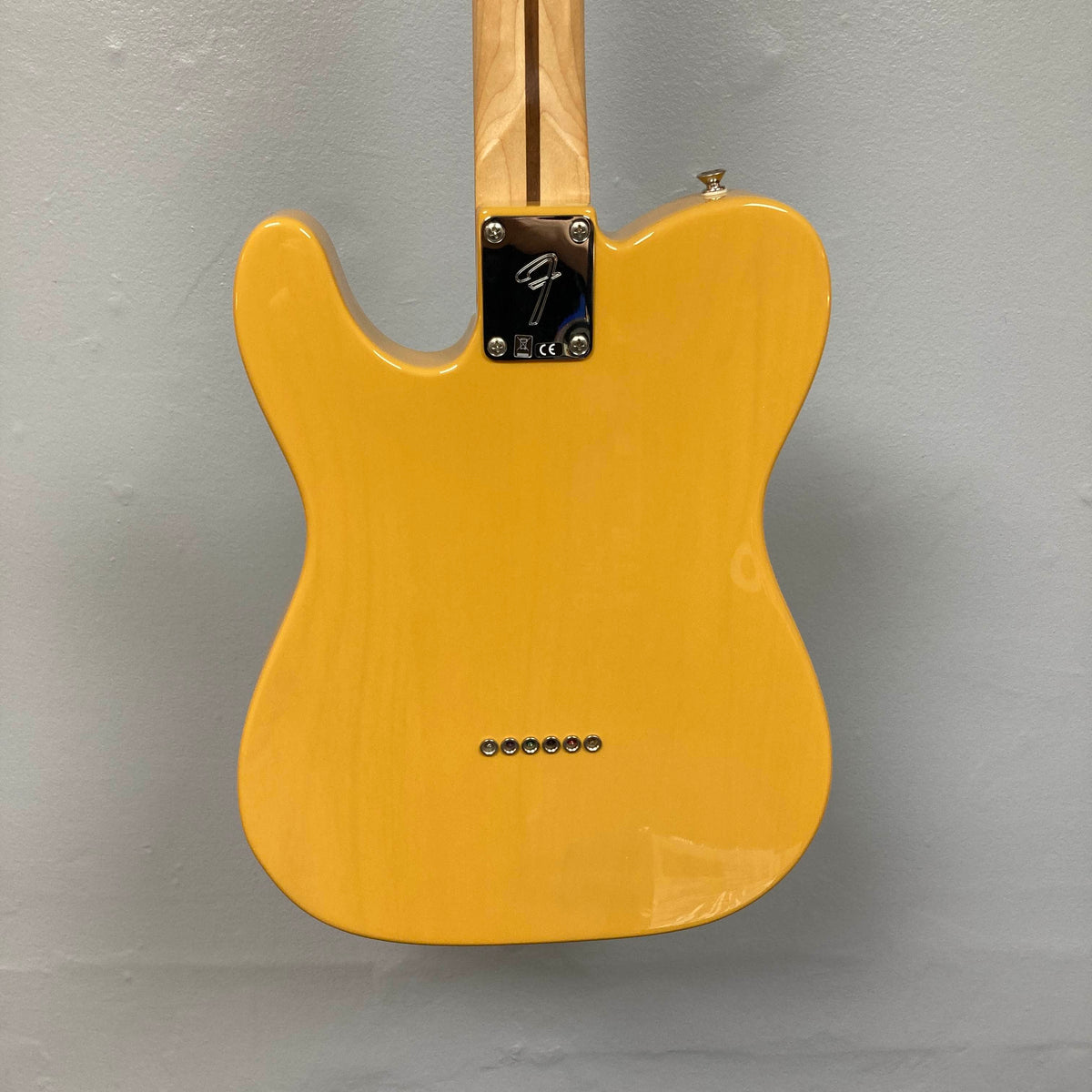 A Fender Player Telecaster 75th Anniversary Butterscotch Used electric guitar, photographed from the back, showcasing the neck joint, string ferrules, and a metal plate featuring the Fender logo.