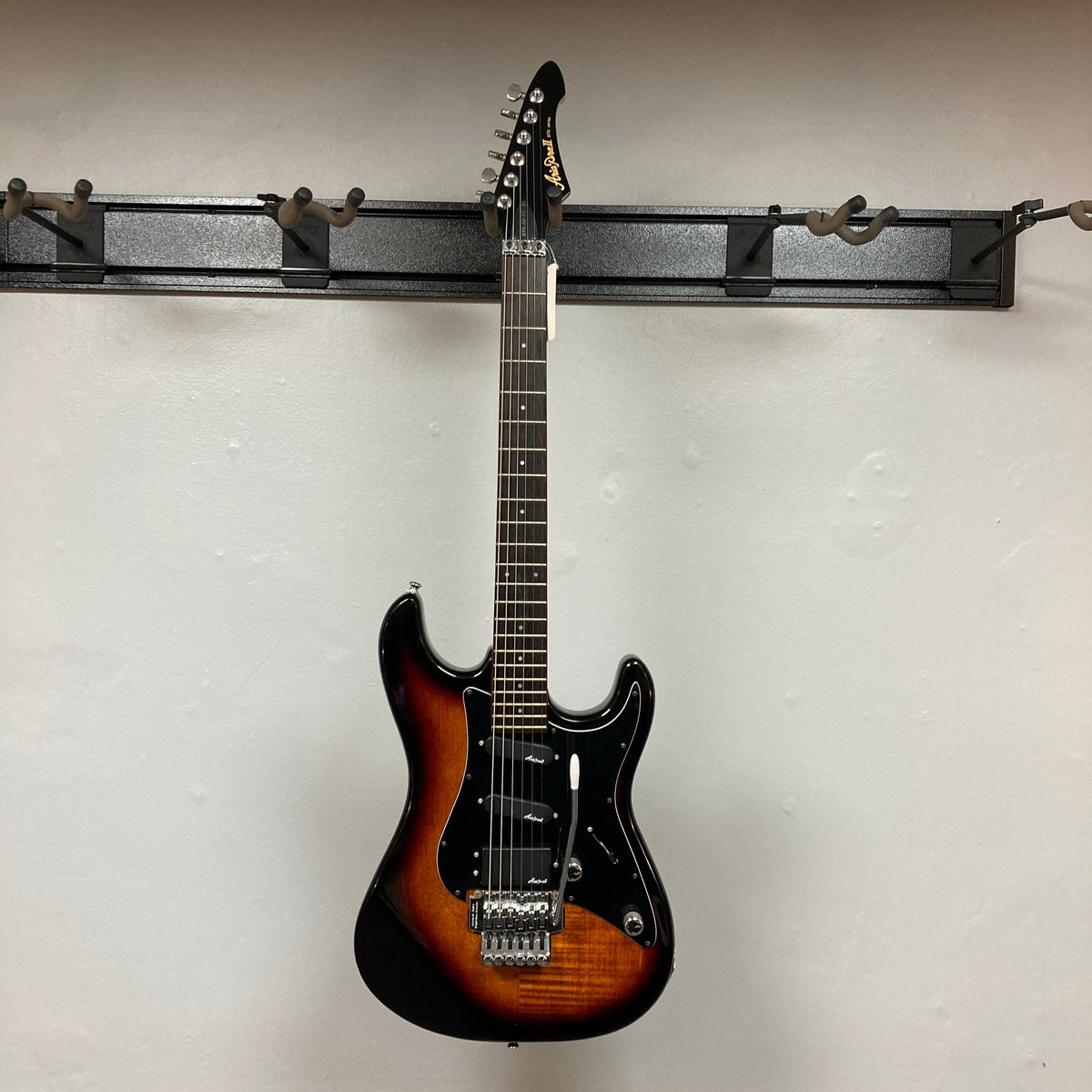 ARIA PRO II STG-02-3C electric guitar, mounted on a wall, showcasing its versatile design with Humbucker-Single-Single pickups and Floyd Rose tremolo system.