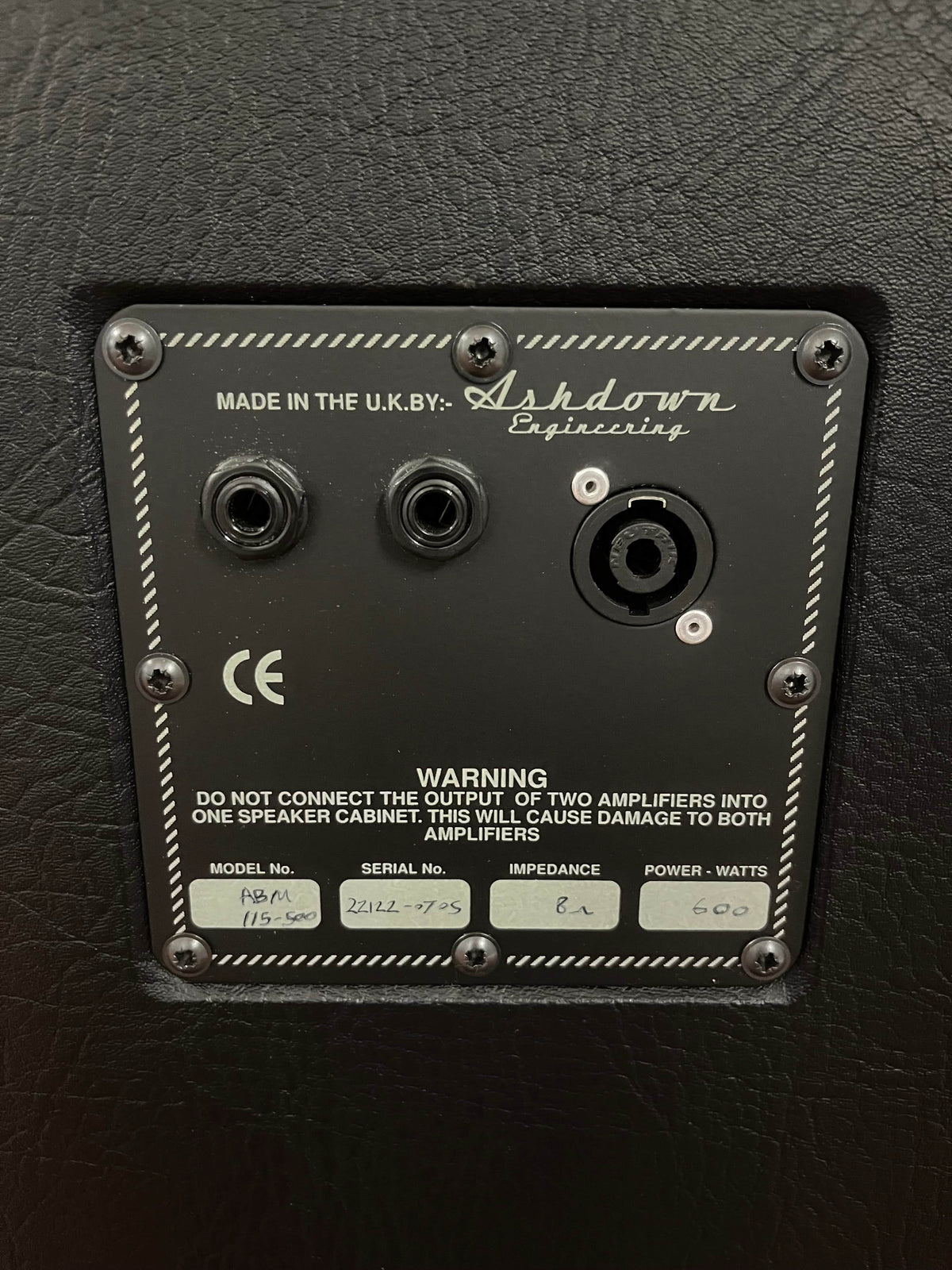 Close-up of the back panel of an Ashdown UK Built ABM Bass Rig Full Stack (EVO II 900 Head, 410T, 115-500) showing input/output jacks, model/serial number labels, and a warning about amplifier connections.