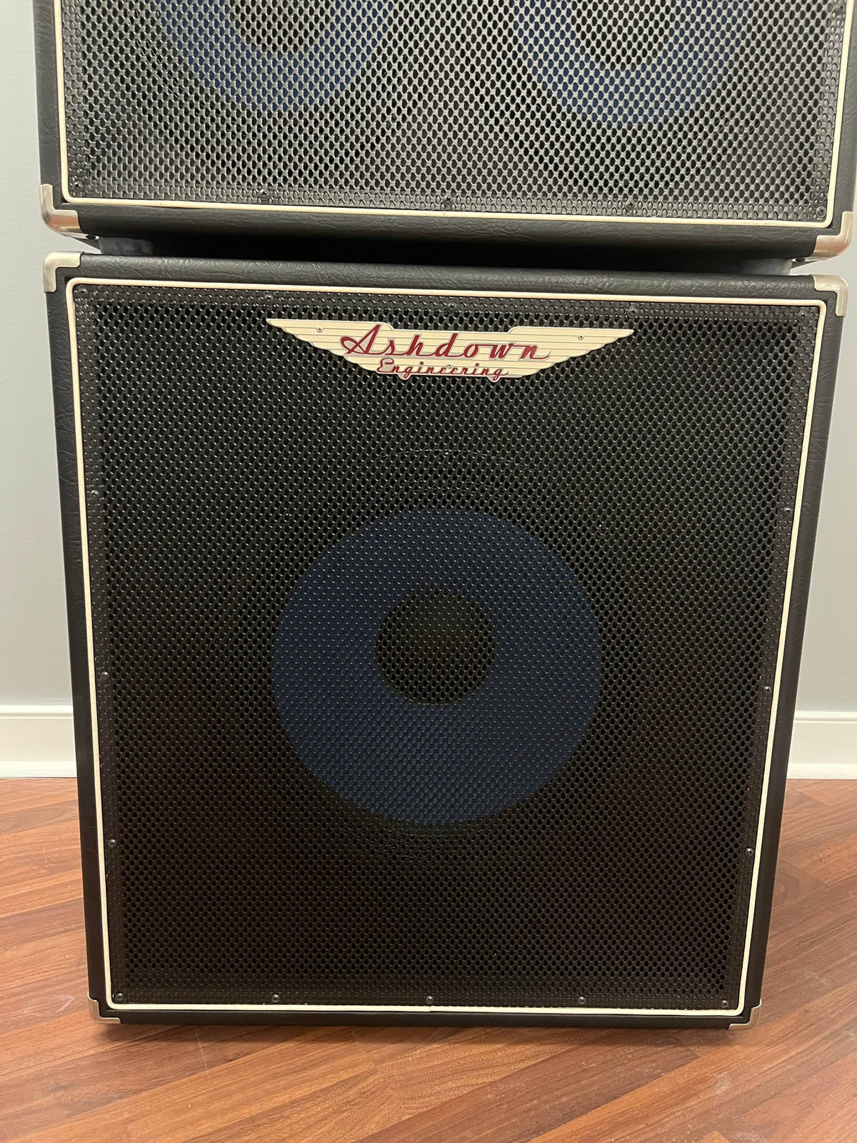 An Ashdown UK Built ABM Bass Rig Full Stack (EVO II 900 Head, 410T, 115-500) in flight cases stands on a wooden floor against a light-colored wall.