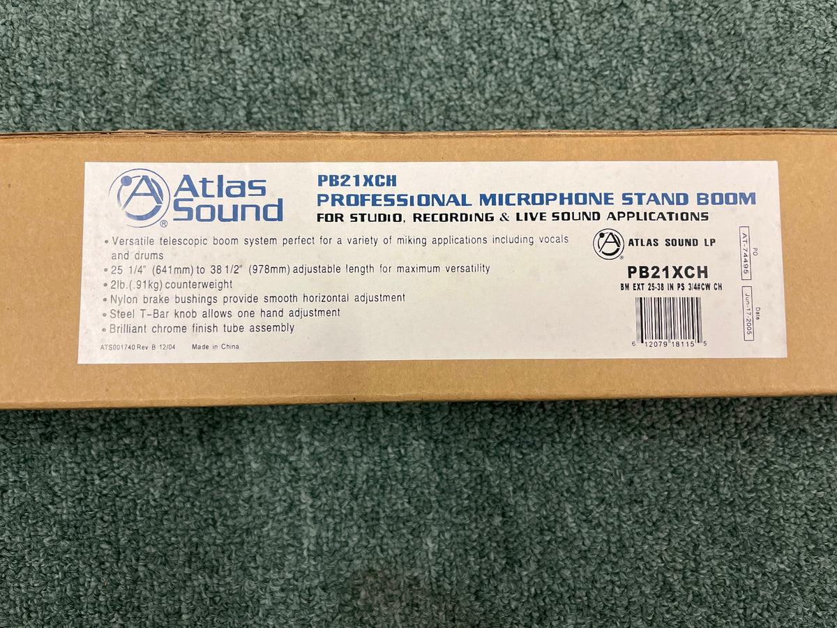 Brown box with Atlas Sound branding, labeled "Atlas Sound PB21XCH Professional Microphone Stand Boom" for studio and live sound use, shown on a green carpet.