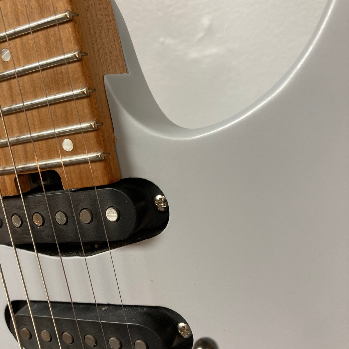 Close-up of a Used Charvel DK24 HSS 2PT CM Electric Guitar - Gray, showing the neck with metal frets and strings, a wooden fretboard, body cutaway, and visible Seymour Duncan pickups. Brand: Charvel.
